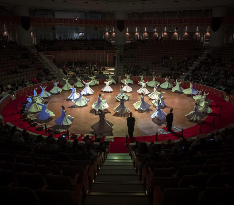 Konya - Turkey, November 19, 2022 , Sufi whirling dervish (Semazen) dances at Mevlana Culture Center. Semazen conveys God's spiritual gift to those are witnessing the ritual.